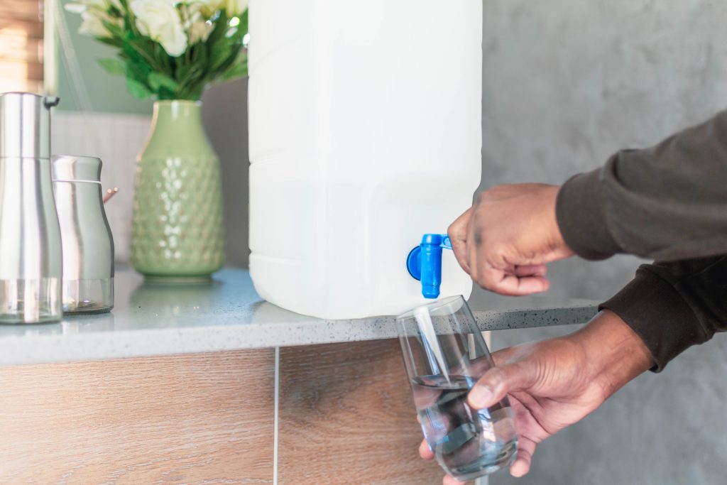 A person pouring water into a glass, highlighting the importance of staying hydrated.
